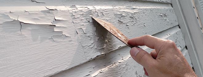 man scraping lead paint off house which can cause lead poisoning side effects