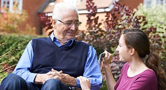 nursing home staff member talking with elderly resident
