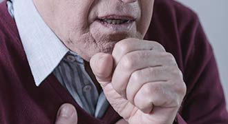 An elderly man coughing after getting an infection at a nursing home.