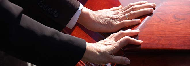 Two hands touching a coffin after a wrongful death at a Rhode Island nursing home.