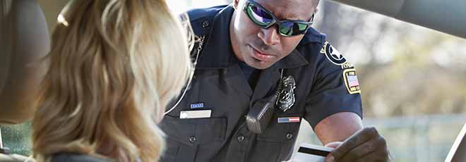 police officer looking at the driver license of a woman pulled over for speeding