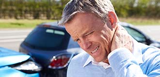A man rubbing his neck in pain after a car accident.