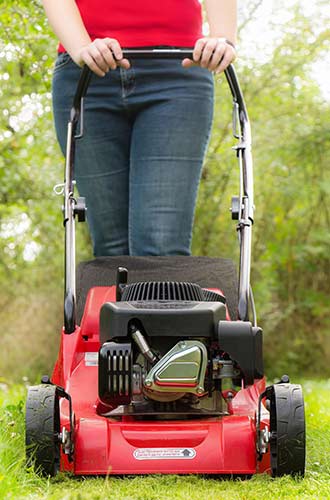 woman using a push mower to cut her lawn