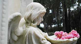 An angel headstone with flowers.