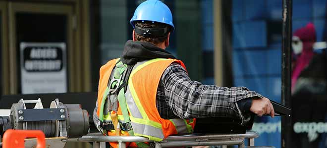 A construction worker with his back turned toward the camera working on a job site.