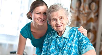 Nursing Home Nurse Hugging Elderly Woman