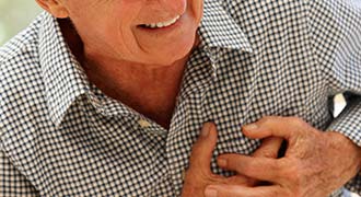 An older man clutches his chest as he suffers from a heart attack.