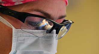 A surgeon wearing a mask and eyewear.