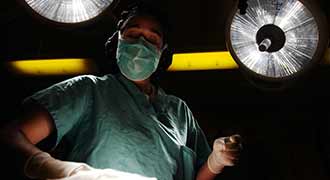 A surgeon standing in a dimly lit room.