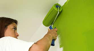 Woman painting wall with latex paint to avoid lead poisoning by using lead paint