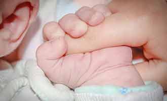 Holding the hand of a newborn with PPHN.