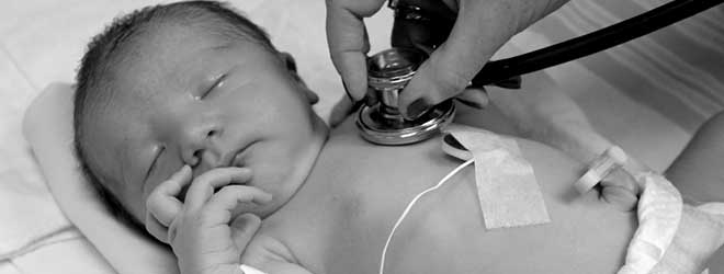A doctor checking a newborn's heartbeat with a stethoscope.