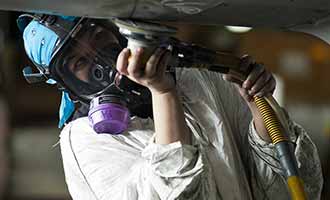 A worker is buffing metal with a tool.