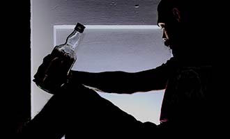 A silhouette of a person drinking liquor.