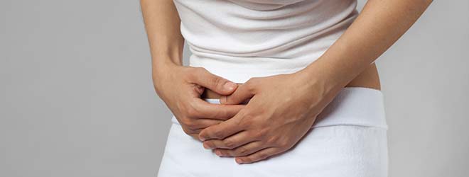 A person is holding their stomach in pain as they suffer from irritable bowel syndrome. 