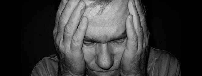 A person with a headache holding their head with both hands.