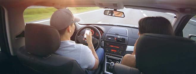 man texting while driving which in one of many dangerous types of distracted driving