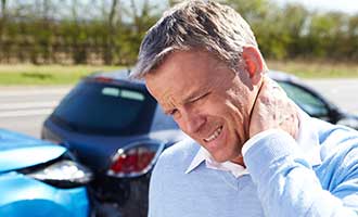 A man rubbing his neck in pain after a car accident.