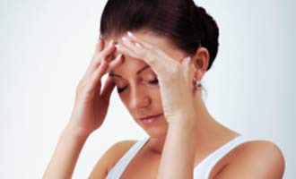 A woman with a headache holds her head with both hands.