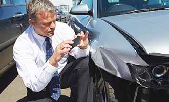 man photographing property damage to car