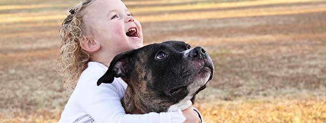 child hugging pitbull