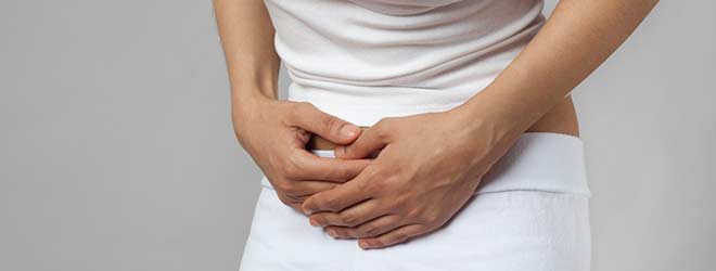 A person is holding their stomach in pain as they suffer from a medical device side effect.