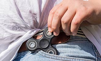 A person with a fidget spinner sticking out of jean pocket.