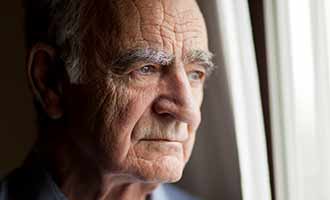 Elderly man looking out of a nursing home