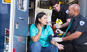 A woman is being examined by two EMTs in the back of an ambulance after being in a car accident.