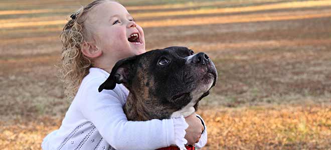 Child hugging a friend's dog