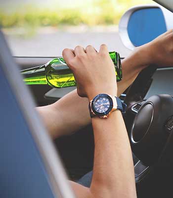 Young driver drinking alcohol while driving
