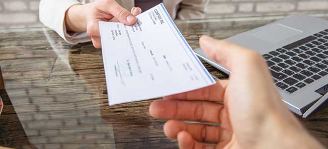 A personal injury lawyer handing their client a settlement check.