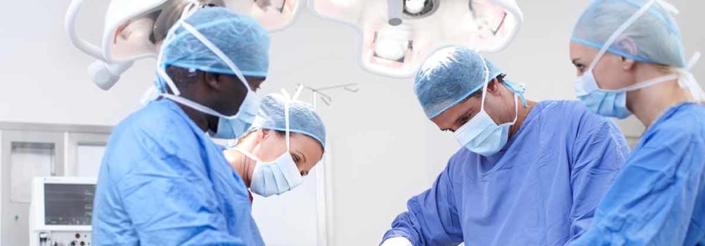 Four surgeons are operating on a patient inside a hospital.