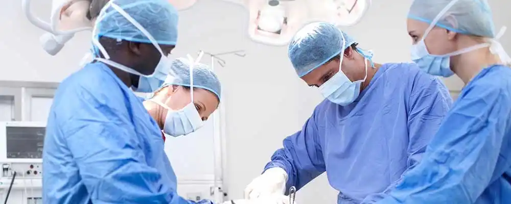 Four surgeons are operating on a patient inside a hospital.