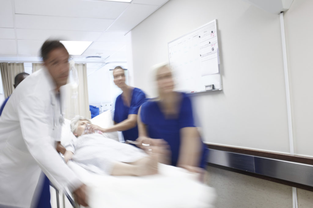 A woman in a hospital bed is being rushed through the hallways by doctors.
