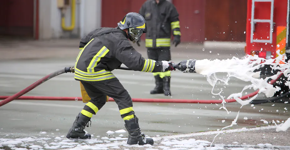 A firefighter holding a hose that's shooting out foam