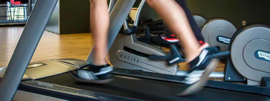 Focus is on a person's legs as they run on a treadmill.