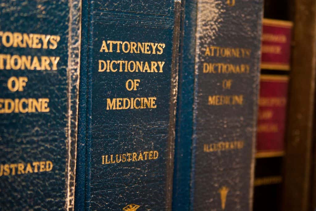 A row of books labeled "Attorneys' Dictionary of Medicine" is on a Social Security disability attorney's desk.