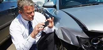 A man taking photos of his damaged car after a car accident. 
