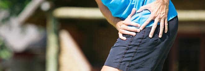 A runner holding his hip in pain.