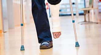 Focus is a person with a leg cast walking with crutches.