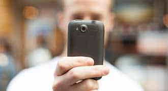 A Massachusetts motorcycle accident lawyer is taking a photo with his smartphone.