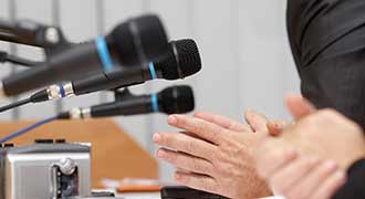A panel of people talking into microphones. 