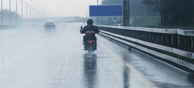 A motorcycle driving down the highway in rain.