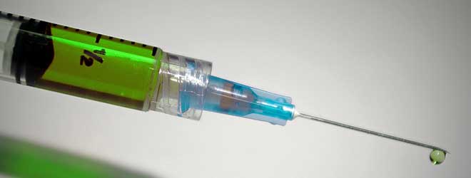 A needle pushing out a drop of liquid.