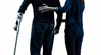A man being assisted as he walks with a cane. 