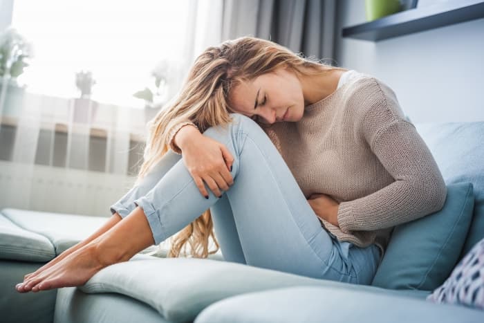 A woman holding her stomach in pain. 