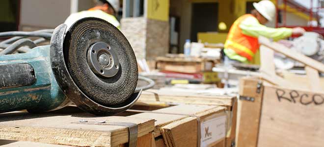 A Rhode Island construction accident lawyer documents the scene of a construction site. There's a worker in the background, and the focus is on a table saw.