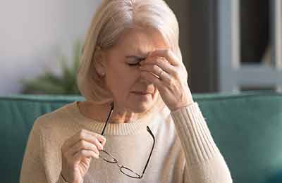A woman holding the bridge of her nose in pain. 