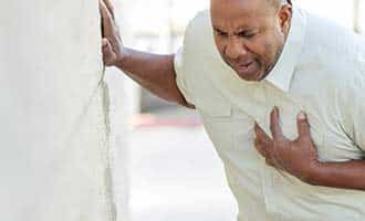 A man clinching his chest in pain from a heart attack. 